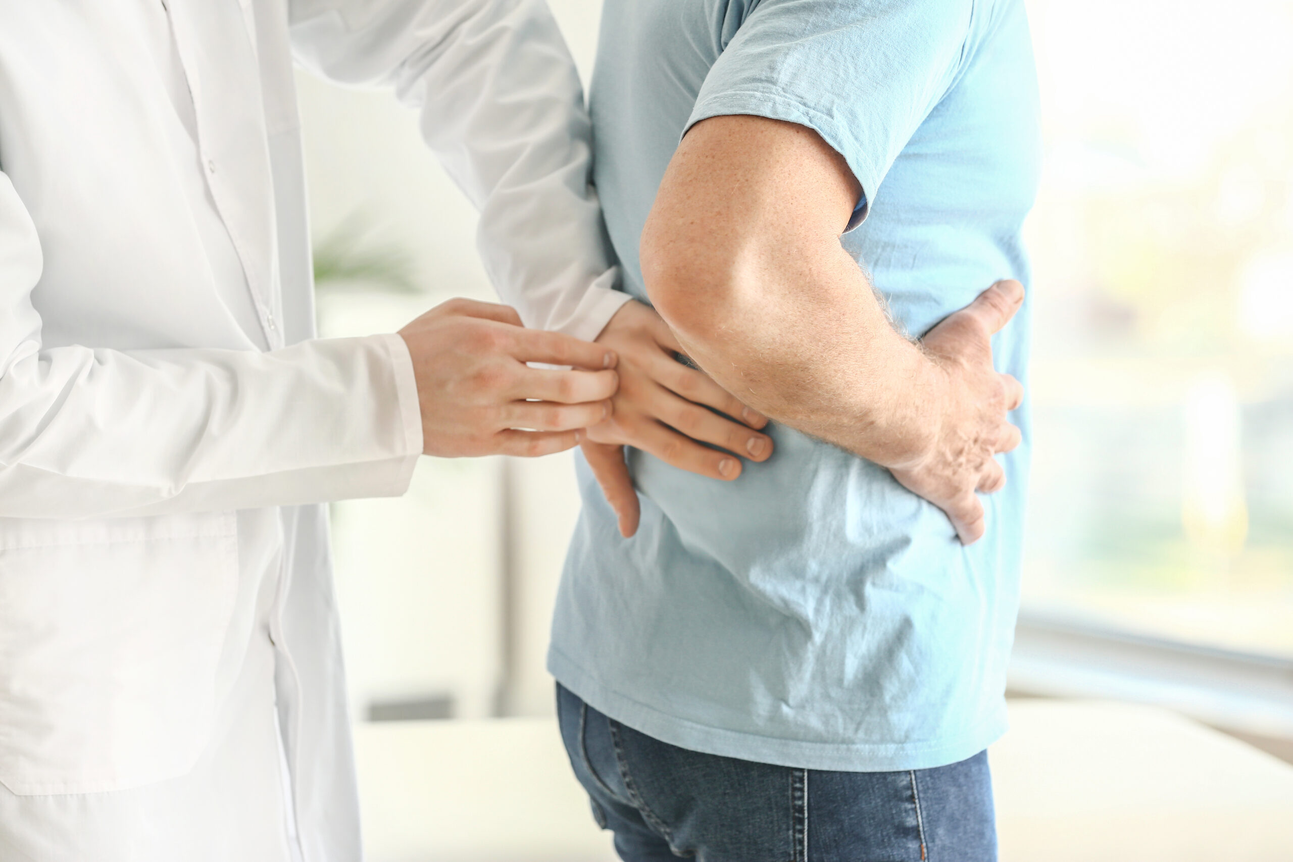 Urologist examining male patient in clinic